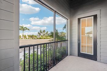 A balcony with a black railing and a view of a street with palm trees